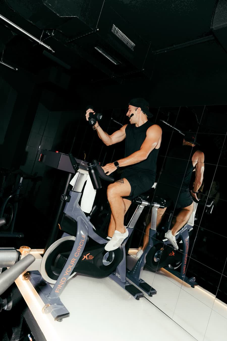 Il coach sul podio dello studio GYRU di Milano, in sella con i pesi in mano